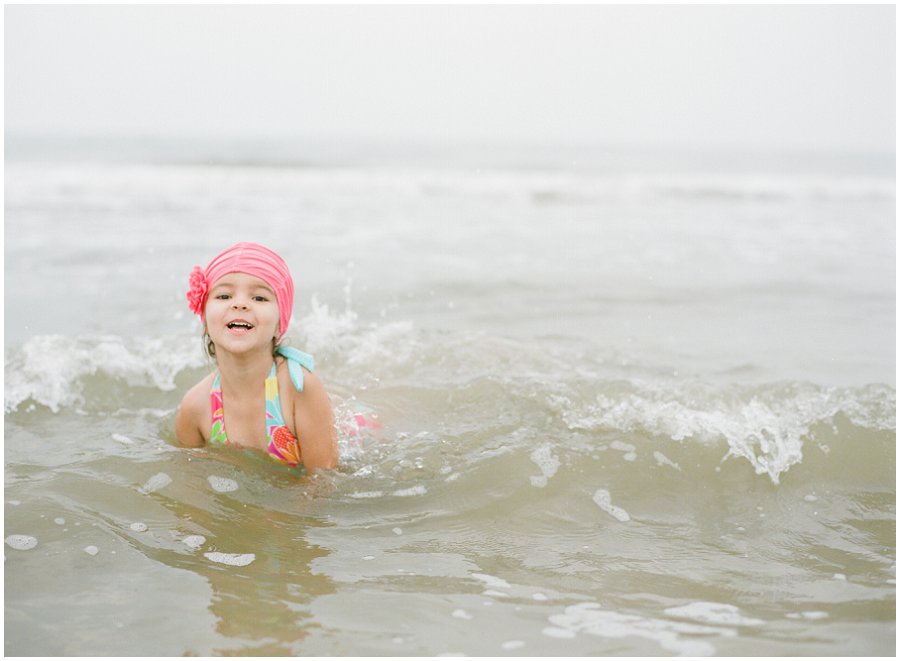 Pink swim cap on little girl as she plays at the beach.
